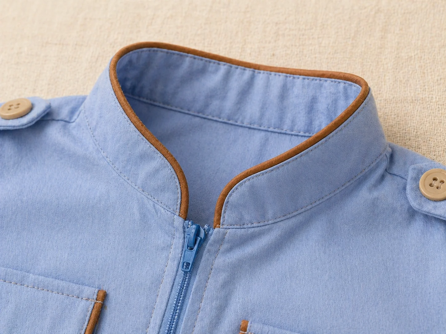 Macro da gola padre arredondada azul claro com vivo cobre · zíper frontal · lapelas com botão